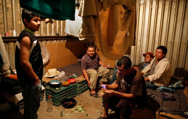 Laborers at Campo San Emilio, Sinaloa, sleep in their windowless rooms on vegetable crates and scraps of cardboard. Juan Hernandez, far right, wanted to visit his ailing wife in Veracruz. "But if I leave, I lose everything," he says.